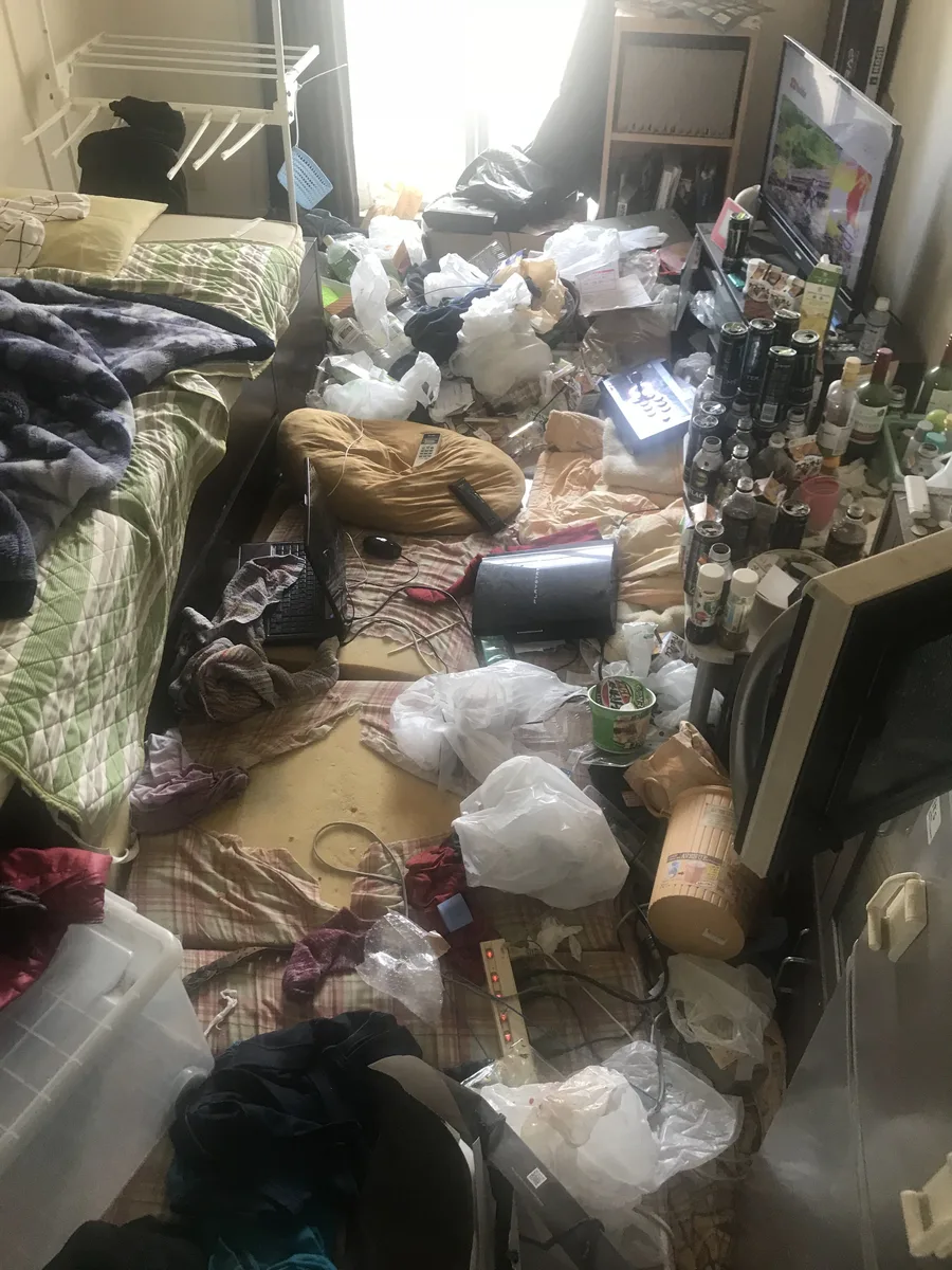 ゴミ屋敷清掃前の1Kアパート居室 — ゴミや不用品で床が見えない状態
